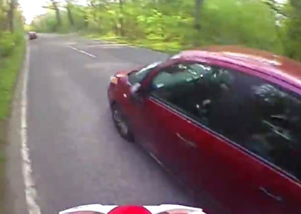 A still from head-cam footage of a car overtaking a cyclist too close