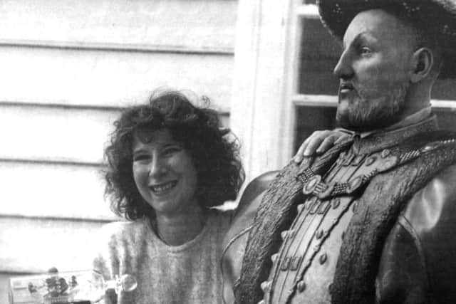 Jean Pallet holds her ship in a bottle, alongside a statue of Henry VIII