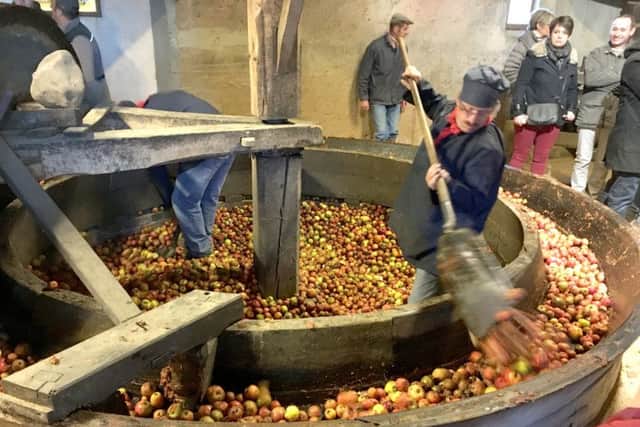 A resident of Le Sap pulps apples at the towns cider festival. Below, Dive-sur-Mer, where William the Conqueror set off in 1066, on market day.