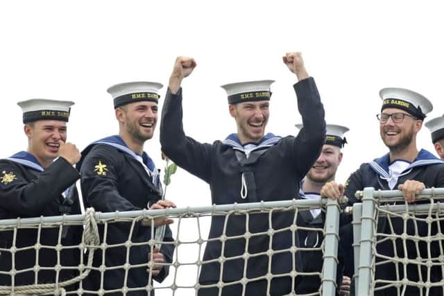 Sailors on the deck of HMS Daring cheer as she returns home to Portsmouth after a nine month mission