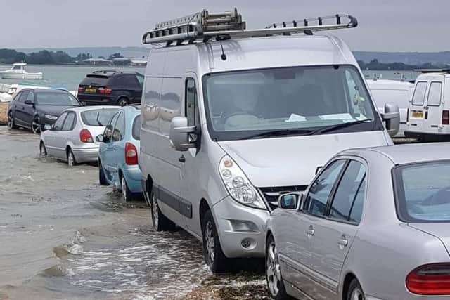 The tide reaches vehicles parked at the beach