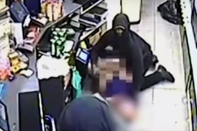 The two men are seen attacking a worker behind the shop counter. Picture: Sussex Police