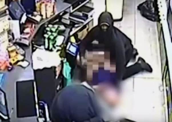 The two men are seen attacking a worker behind the shop counter. Picture: Sussex Police