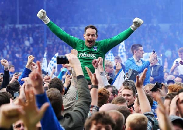David Forde is hoisted loft the heads of Pompey fans who made their way on to the pitch at Fratton Park after the League Two title was won Picture: Joe Pepler