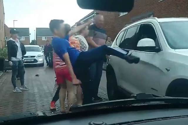 A young boy is filmed kicking out at the car's side mirror as it goes past.