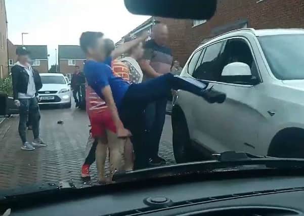 A young boy is filmed kicking out at the car's side mirror as it goes past.