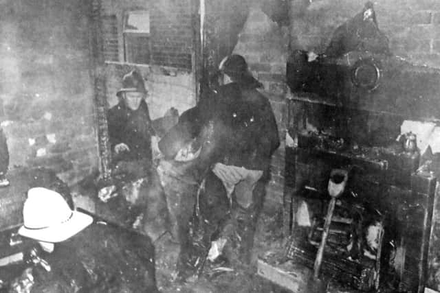 Firemen clear away debris in the smoke-filled room where the fire broke out