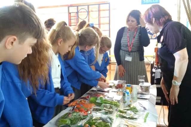 Denmead Junior School pupils learn more about fresh vegetables, above, and below pupils from Bishops Waltham Junior School taste the goods from local producers