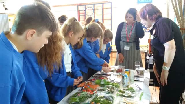 Denmead Junior School pupils learn more about fresh vegetables, above, and below pupils from Bishops Waltham Junior School taste the goods from local producers