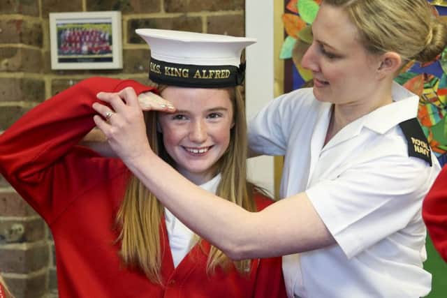 Naval reservist and teacher AB Emma Cutler helps Isobel Turner, 11, to salute.   PHOTO: Royal Navy