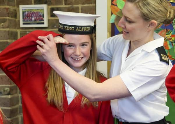 Naval reservist and teacher AB Emma Cutler helps Isobel Turner, 11, to salute.   PHOTO: Royal Navy