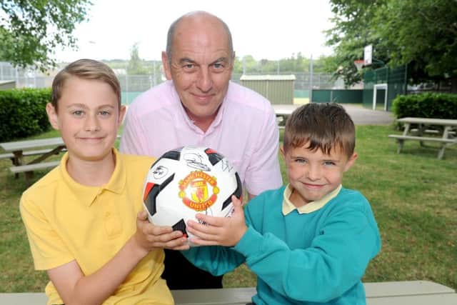 Headteacher Howard Payne with (left) Lenny Horrell, 10, Ryan Hooper, seven, and the signed ball.   Picture: Sarah Standing (170829-4028)