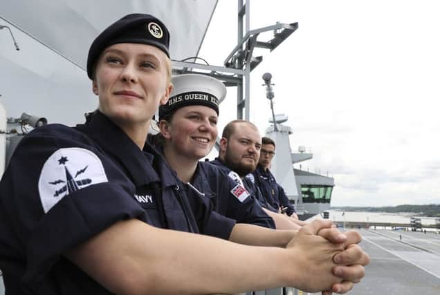 Proud members of the ship's company watch as the giant warship inches her way to sea for the first time. From left, Able Seaman (AB) Natasha Elford, AB Layton Toward and AB Richard Mead