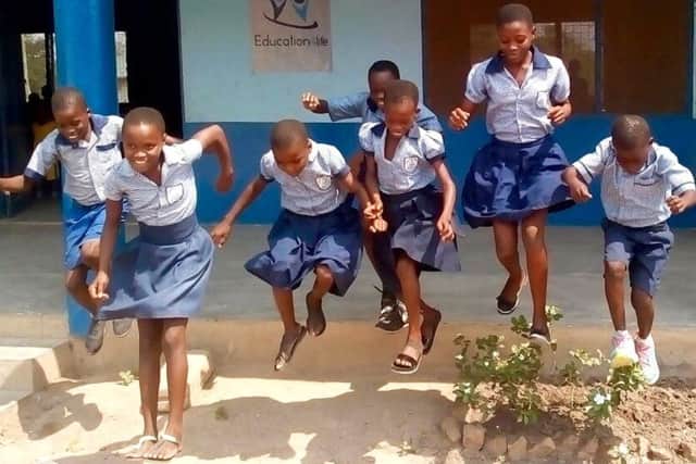 Young girls jumping for joy at a school in Ghana supported by Education4Life, part of Farm4Life