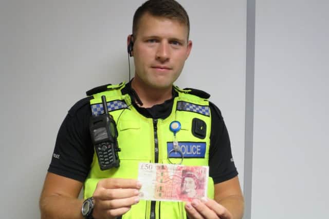 PC David Ronchetti holding a counterfeit £50 note seized in a police investigation