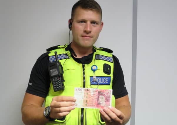 PC David Ronchetti holding a counterfeit Â£50 note seized in a police investigation