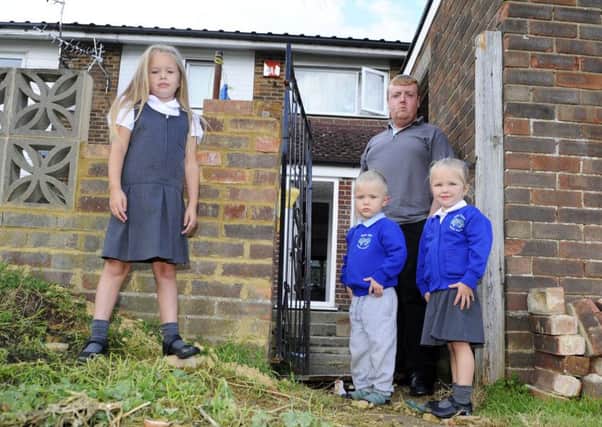 Maddison Betteridge, six, with Luke Betteridge, 25 and three-year-old twins Reggie-Lucas Betteridge and Ruby-Lou Betteridge in their rear garden gateway where the landlord has just started to re-build the fallen pillar. Picture: Malcolm Wells