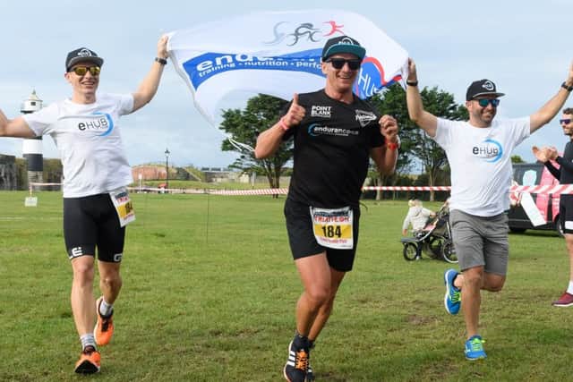 Roman Lacko, left, and Shane Castle with Piotr Meller, centre, as they complete the race and take first place in the relay team event. Picture: Keith Woodland