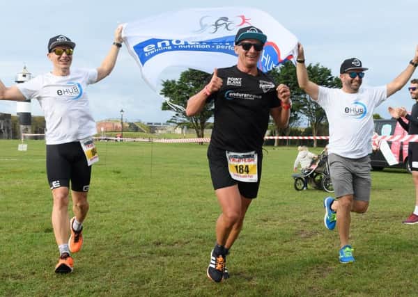Roman Lacko, left, and Shane Castle with Piotr Meller, centre, as they complete the race and take first place in the relay team event. Picture: Keith Woodland