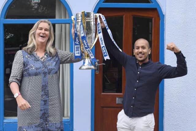 Clare Martin, director of Pompey in the Community, and Faz Ahmed of The Akash holding the League Two trophy