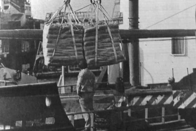A dockyard mobile crane unloads the cargo of cement from the coaster at Flathouse Quay, Portsmouth