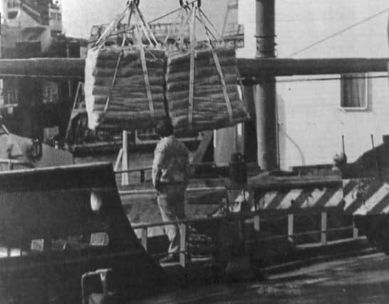 A dockyard mobile crane unloads the cargo of cement from the coaster at Flathouse Quay, Portsmouth