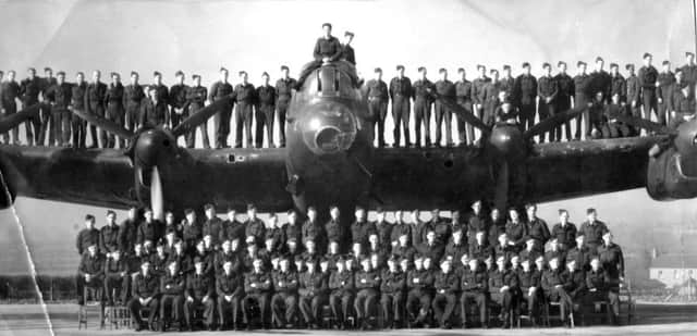 Airmen and  officers pose for the camera on and around a Lancaster bomber.
