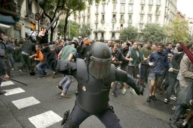 A Spanish riot police officer swings a club against would-be voters near a school assigned to be a polling station by the Catalan government in Barcelona