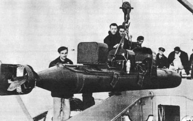 An Italian human torpedo with warhead attached is raised from the hold of an Italian ship.