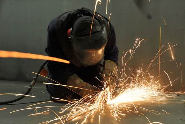 A fitter cutting steel  in the shipbuilding hall at Portsmouth Dockyard